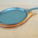 Oval sizzling platter with handle and wooden base